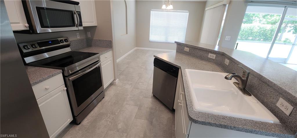 Kitchen with appliances with stainless steel finishes, white cabinetry, and decorative light fixtures