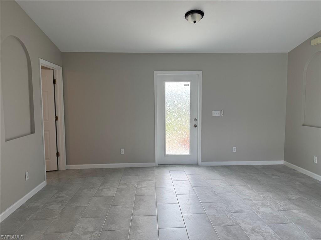 Family room looking at the front door with decorative glass, and entrance to 2nd bedroom on the left