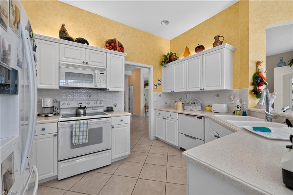 Kitchen featuring white cabinetry, tile flooring, light-toned countertops, and a white tile backsplash