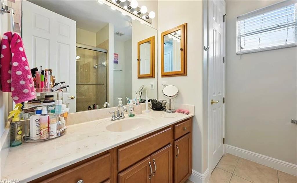 Vanity with integrated sink, wood-finish cabinetry, and a large wall-mounted mirror