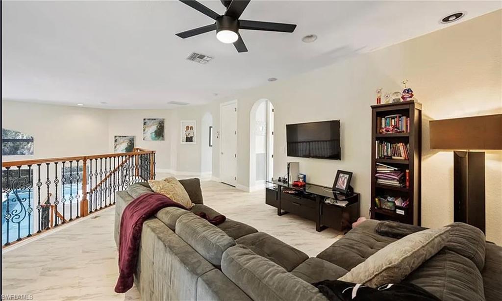 Spacious upper-level area featuring a black ceiling fan, recessed lighting, tile flooring, and a decorative wrought iron and wood banister
