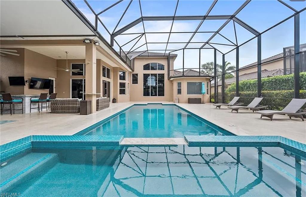 Screened outdoor area featuring a swimming pool, integrated spa, and an expansive patio