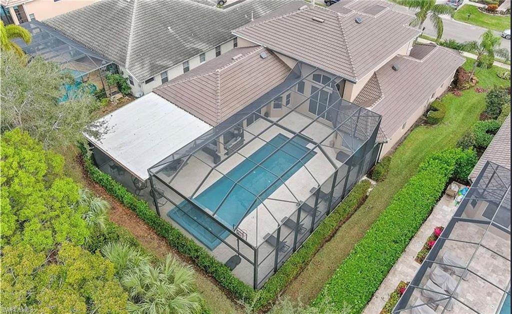 Screen-enclosed swimming pool with a paved deck, bordered by mature landscaping and established green space