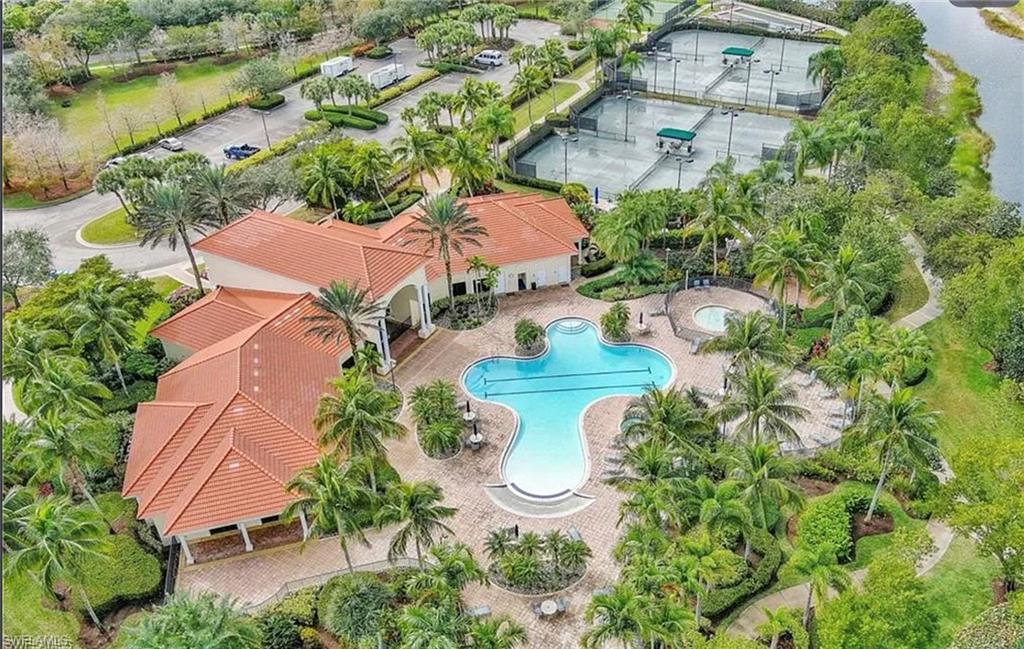Resort-style pool with integrated spa, multiple tennis courts, and a clubhouse building with a tiled roof