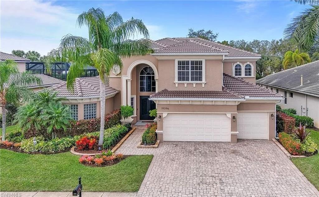 Stucco exterior with a tiled roof, arched entryway, and multiple garage doors