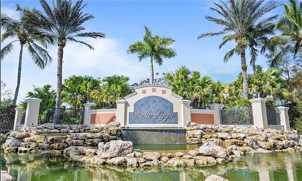 Entry monument with integrated water feature, surrounded by mature palm trees and lush landscaping