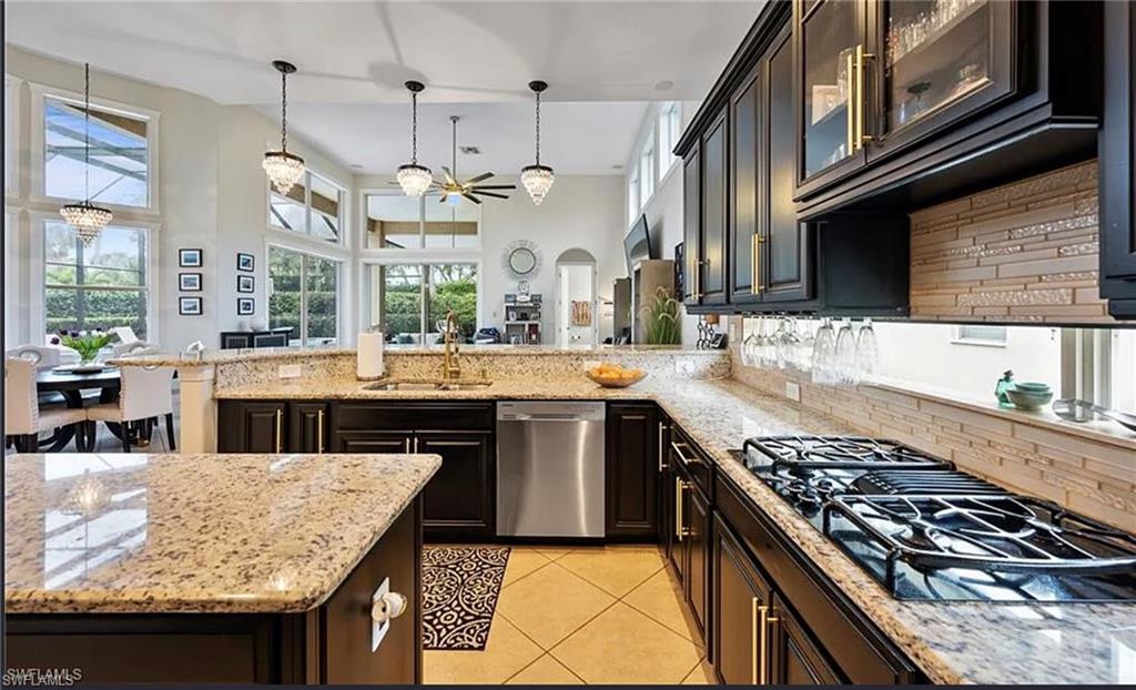 Kitchen featuring dark wood cabinetry, light granite countertops, stainless steel appliances, a gas cooktop, and a tile backsplash