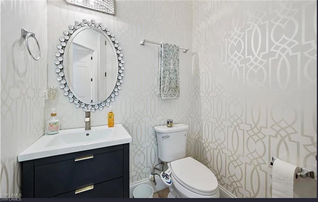 Corner vanity with integrated sink, black cabinetry, chrome faucet, and decorative oval mirror
