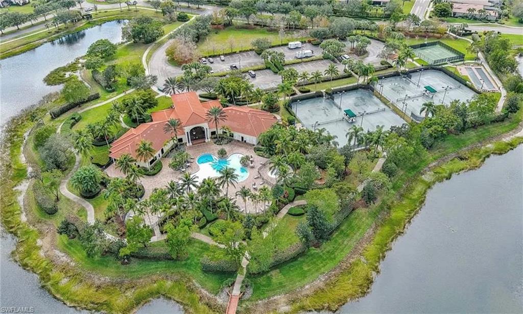 Clubhouse with a terracotta tile roof, a freeform pool, and multiple tennis courts