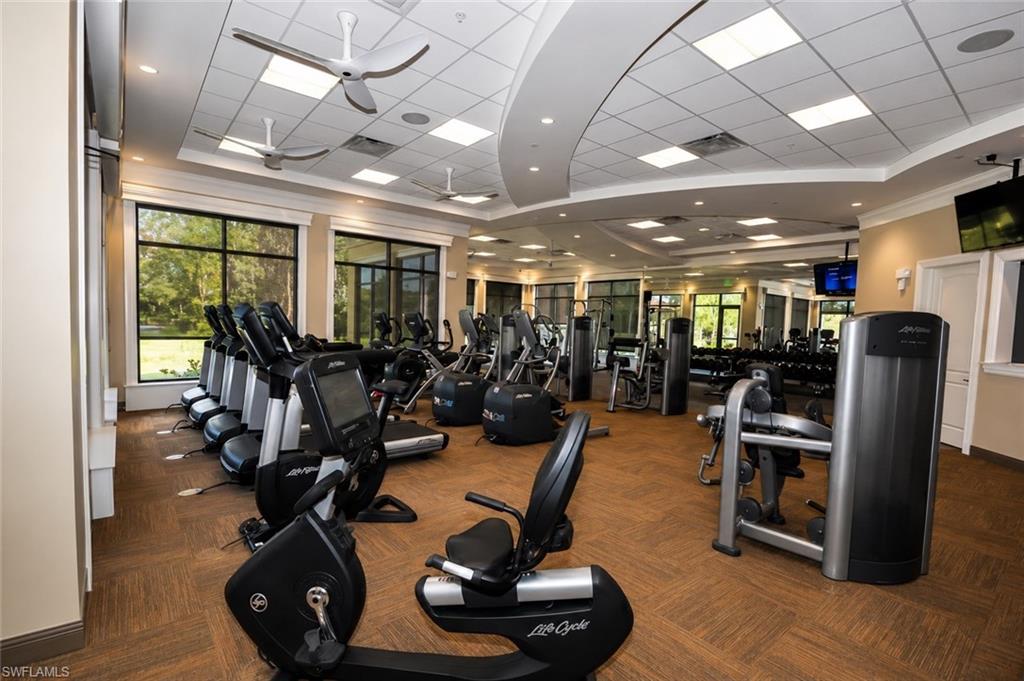 Fitness center with extensive exercise equipment, recessed ceiling lighting, ceiling fans, large windows, and neutral tone walls