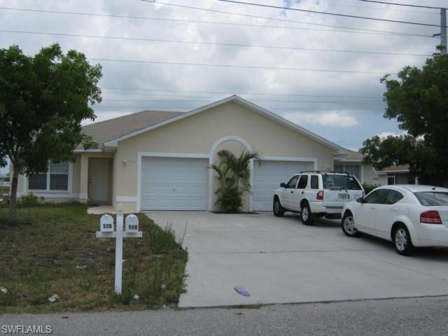 Single-story stucco exterior with dual garage doors, a concrete driveway, and a mailbox structure