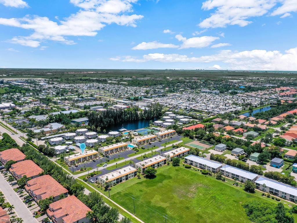 Aerial view of a residential community featuring multiple multi-story buildings, a central parking area, and a swimming pool