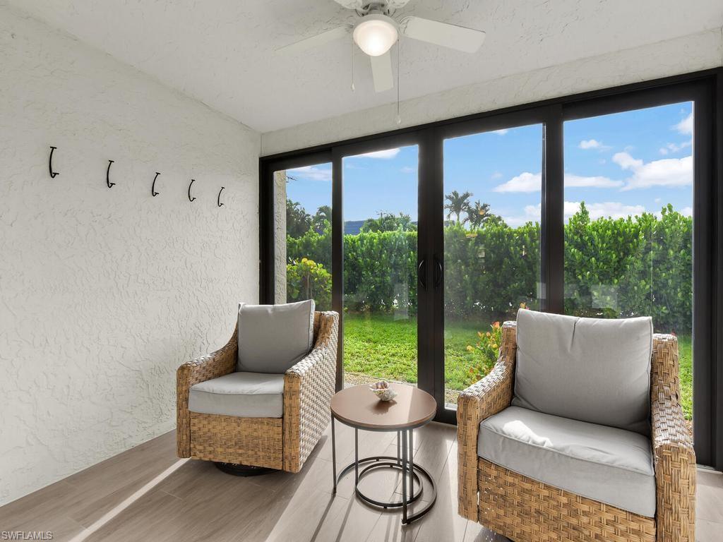 Enclosed patio featuring expansive sliding glass doors, textured wall finishes, a ceiling fan with integrated lighting, and wood-finish flooring