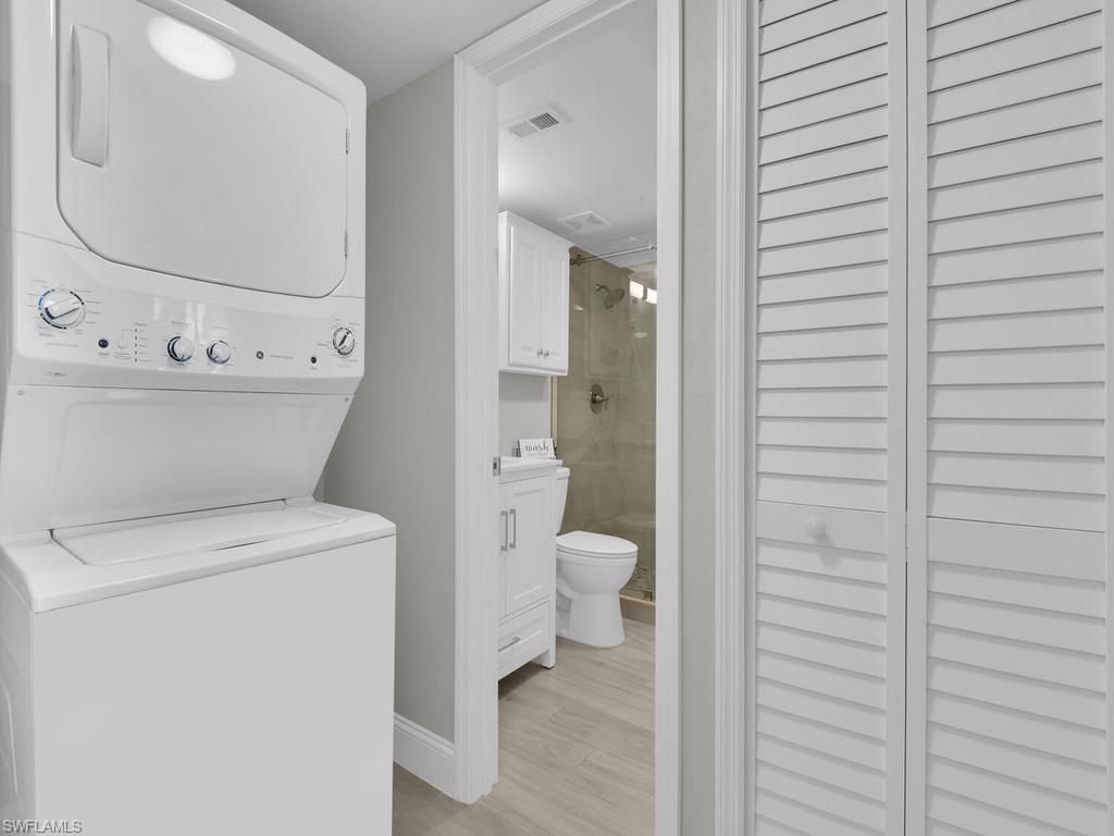 Integrated laundry area featuring a stacked washer and dryer unit
