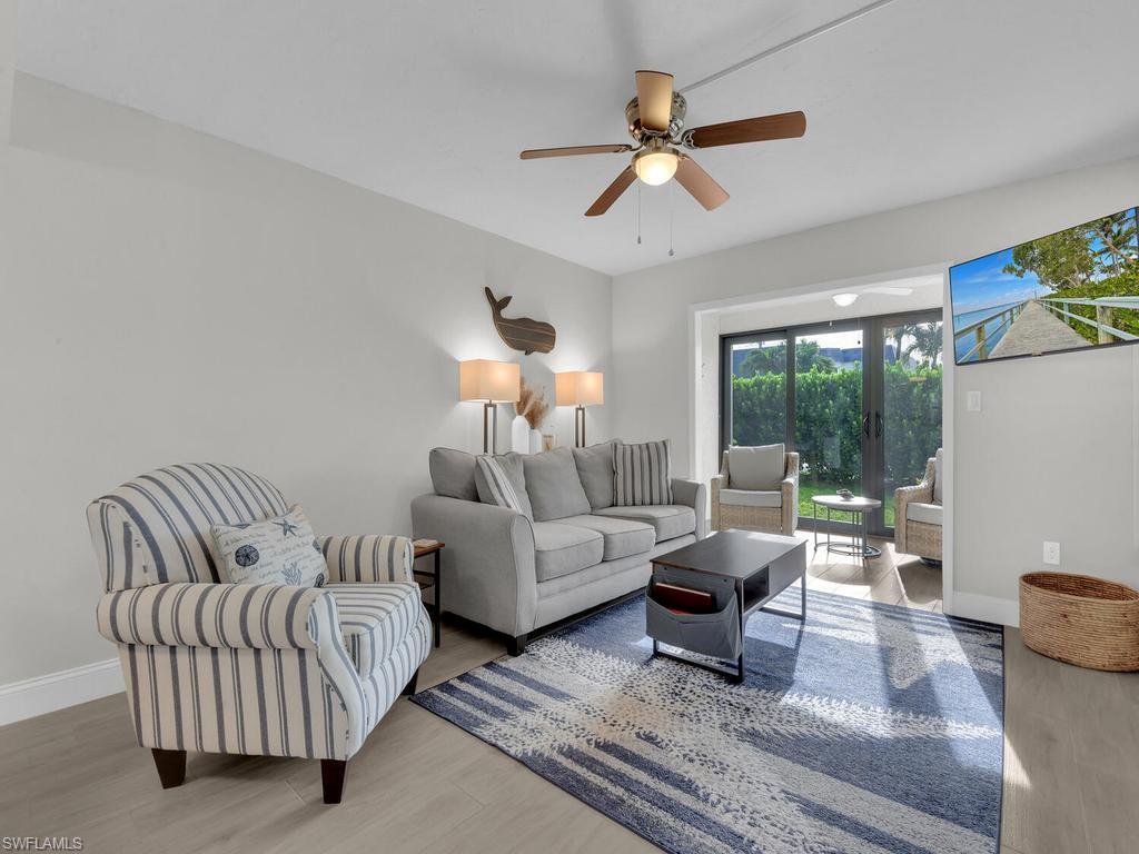 Living area with light wood-finish flooring, white baseboards, and a ceiling fan with integrated lighting