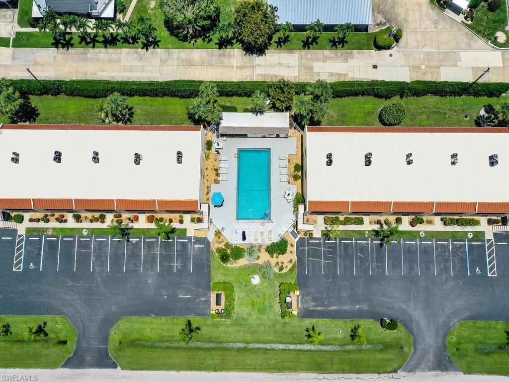 Central swimming pool surrounded by a paved deck with lounge seating and shade structure