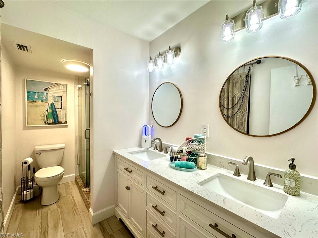 Full bath featuring double vanity, a walk-in shower, and premium surface countertops