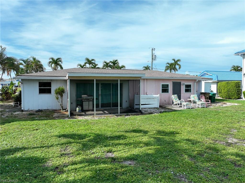 Brick exterior with a screened porch, multiple palm trees, and a paved parking area