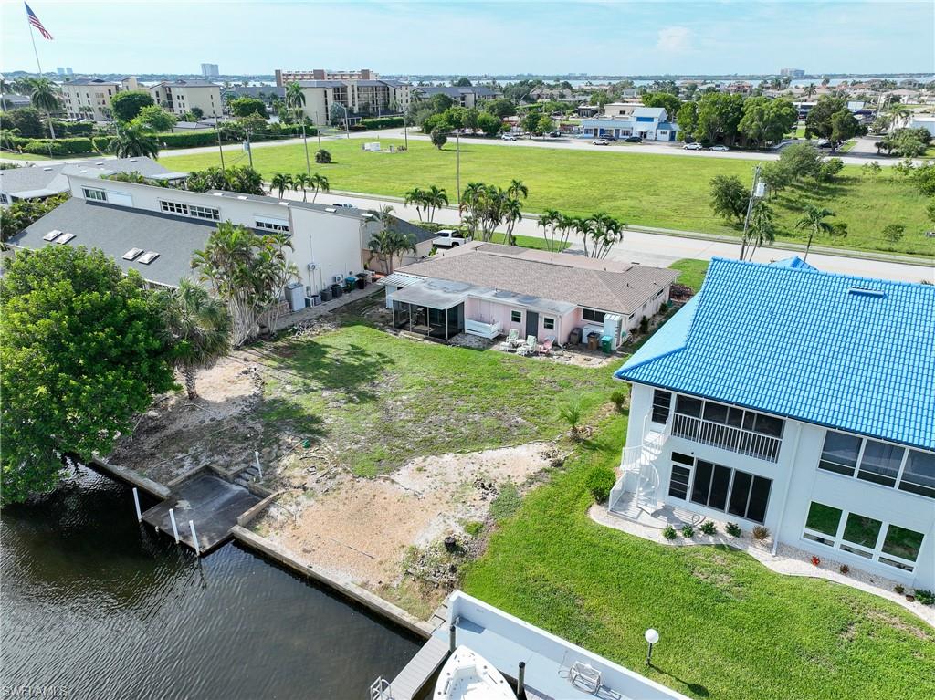 Waterfront property featuring mature landscaping with lush green grounds, a deep-water dock with boat lift, and a bright blue metal roof residence