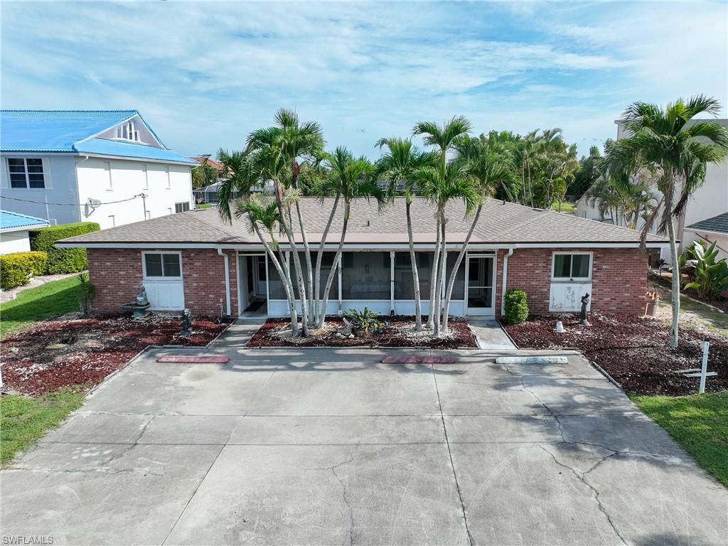 Spacious single-story residence featuring a sprawling lawn with mature palm trees, covered entry porches, and multiple windows providing natural light throughout