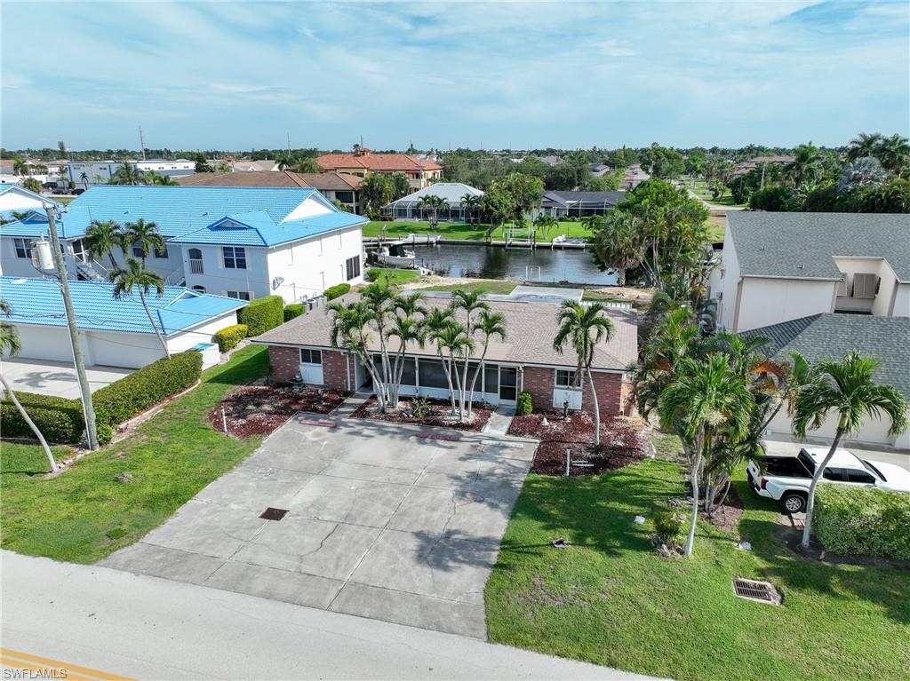 Brick-finish facade with an attached screened-in porch, mature palm trees, and a concrete driveway