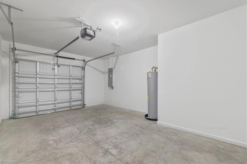 Garage featuring a garage door opener, gas water heater, electric panel, and baseboards