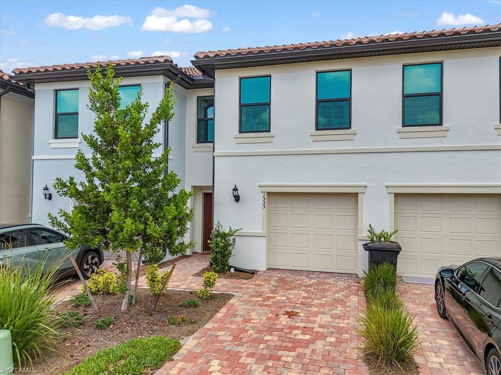 Multi unit property with driveway, an attached garage, stucco siding, and a tiled roof