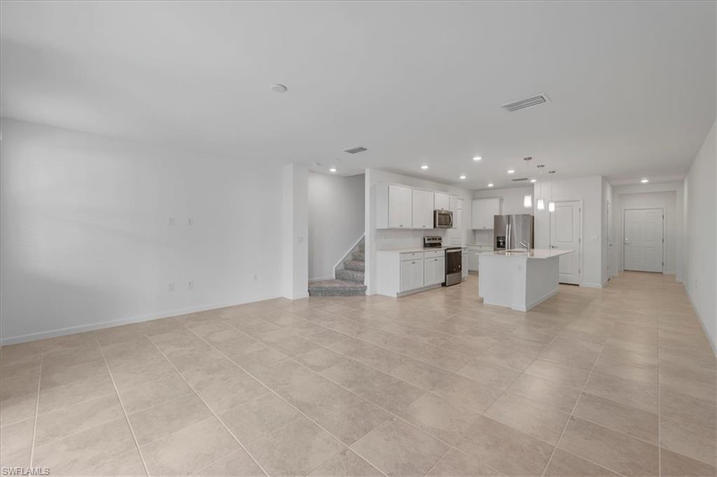 Unfurnished living room with recessed lighting, stairs, baseboards, and light tile patterned flooring