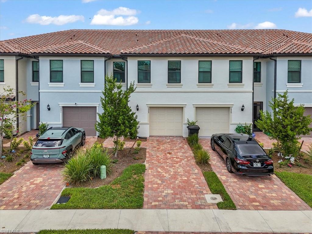 Multi unit property with driveway, a garage, stucco siding, and a tiled roof