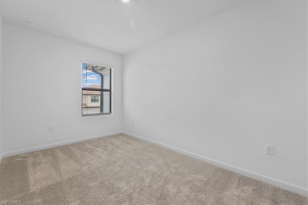Spare room featuring carpet flooring and baseboards