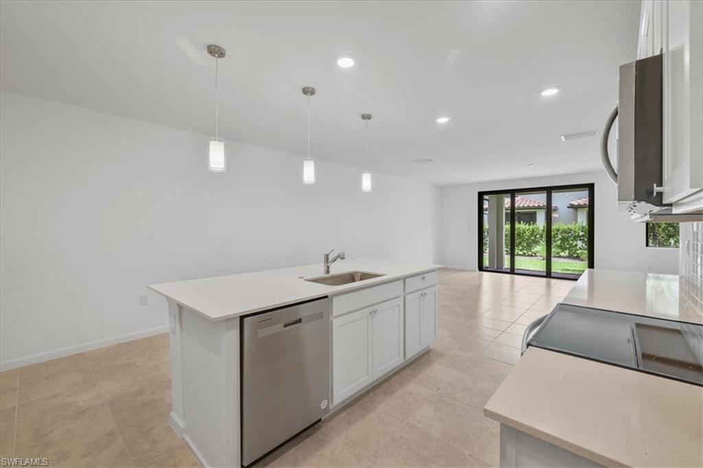 Kitchen featuring stainless steel appliances, a sink, light countertops, white cabinets, and open floor plan