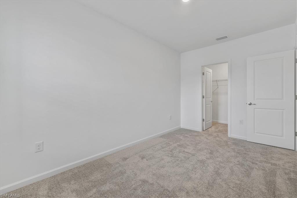 Unfurnished bedroom featuring carpet floors, baseboards, a walk in closet, and a closet