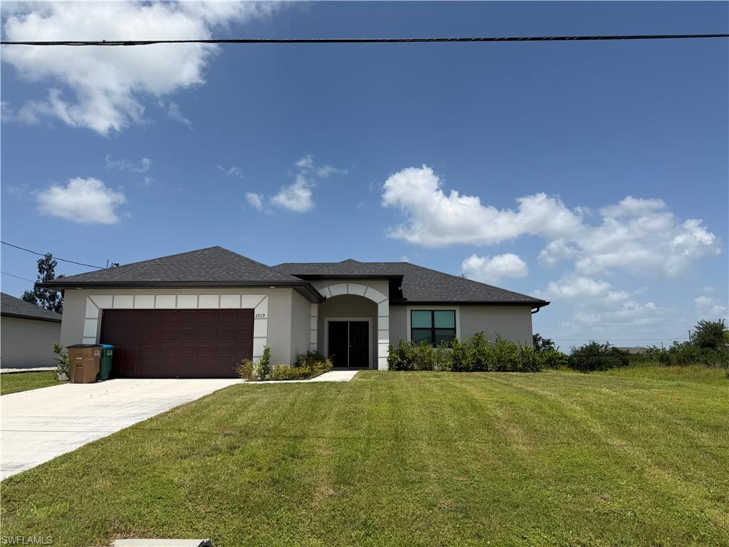 Single-story residence featuring a dark asphalt shingle roof, a two-car garage with a brown door, and a light-colored stucco exterior