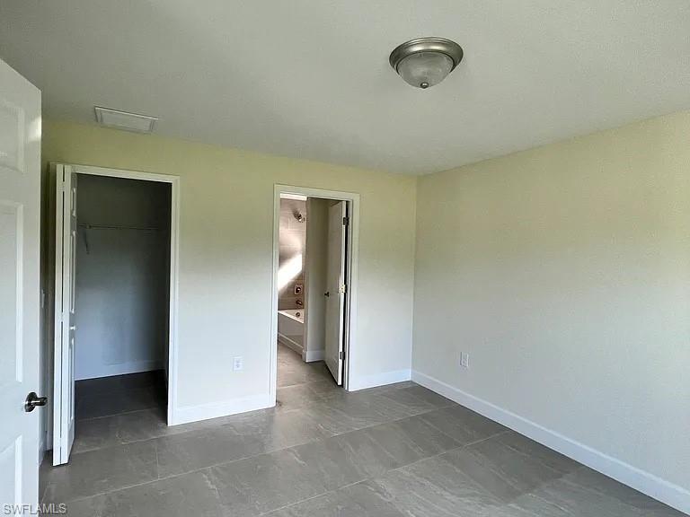 Spacious interior featuring neutral-toned walls, slate-finish tile flooring, recessed ceiling lighting, and multiple doorway openings that define distinct room zones