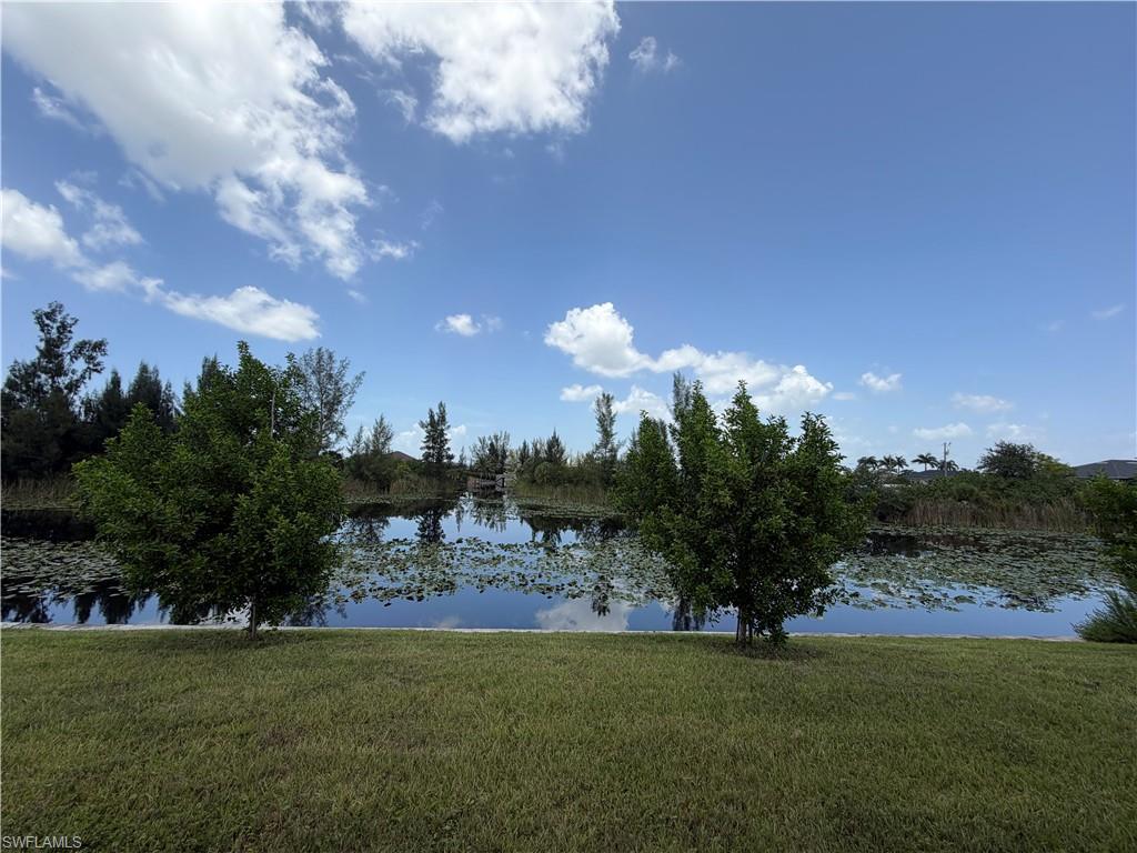 Manicured lawn extending to a tranquil water feature, surrounded by mature trees and natural vegetation