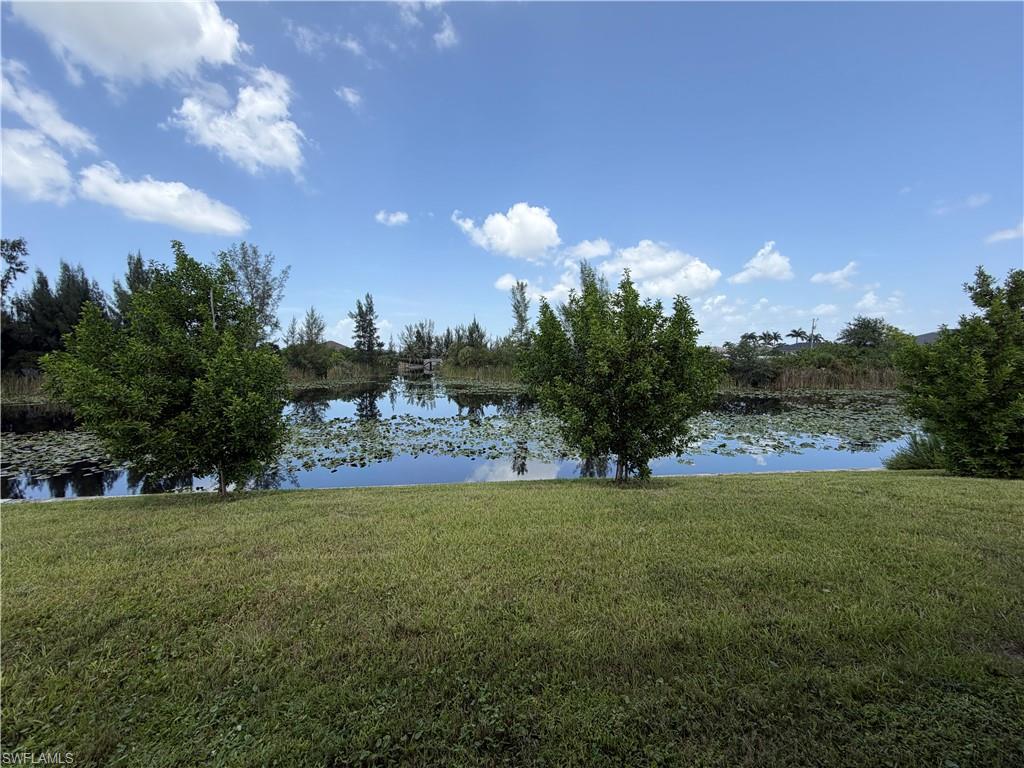Expansive lawn area fronting a reflective waterway, bordered by mature trees and natural foliage