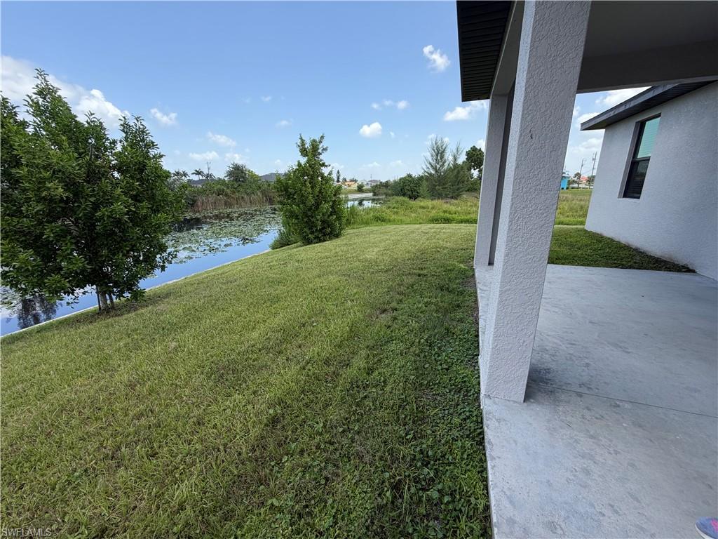 Exterior stucco finish, covered patio, concrete patio surface, water feature, and maintained lawn