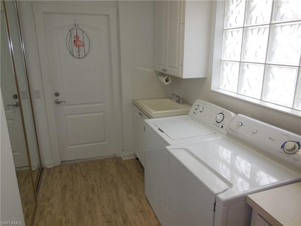 Washroom with a sink, light wood finished floors, cabinet space, and washer and clothes dryer