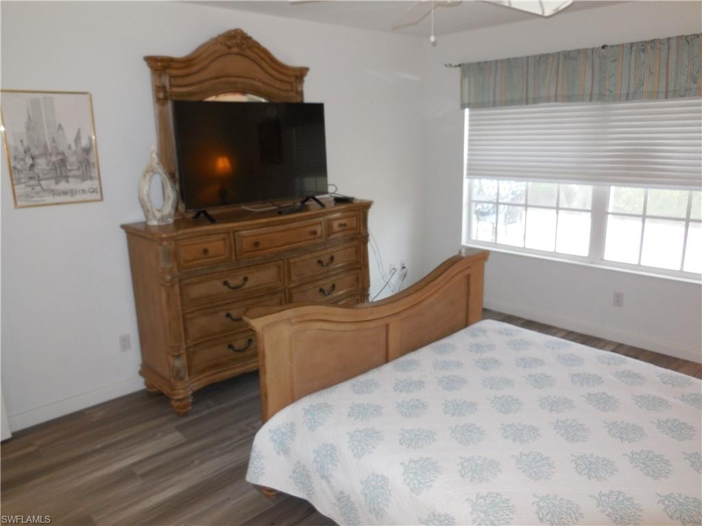 Bedroom featuring a ceiling fan, baseboards, and dark wood finished floors