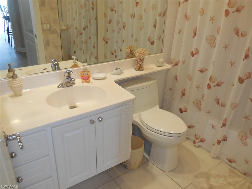 Bathroom featuring toilet, tile patterned floors, curtained shower, and vanity