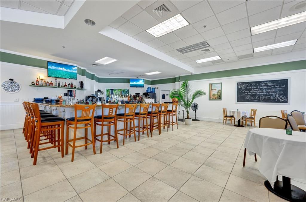 Dining space featuring visible vents, a wainscoted wall, light tile patterned flooring, and a community bar