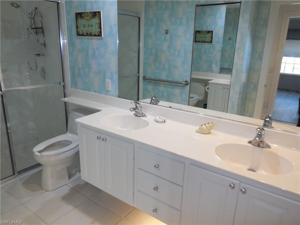 Bathroom with tile patterned flooring, a sink, a stall shower, and toilet
