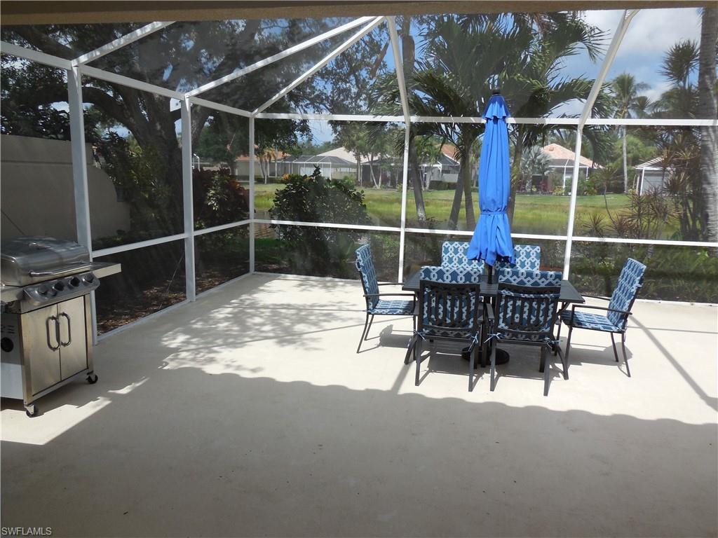 View of patio / terrace with glass enclosure, outdoor dining space, and a grill