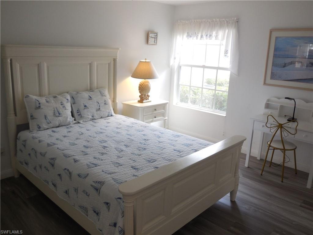 Bedroom with dark wood-type flooring and baseboards