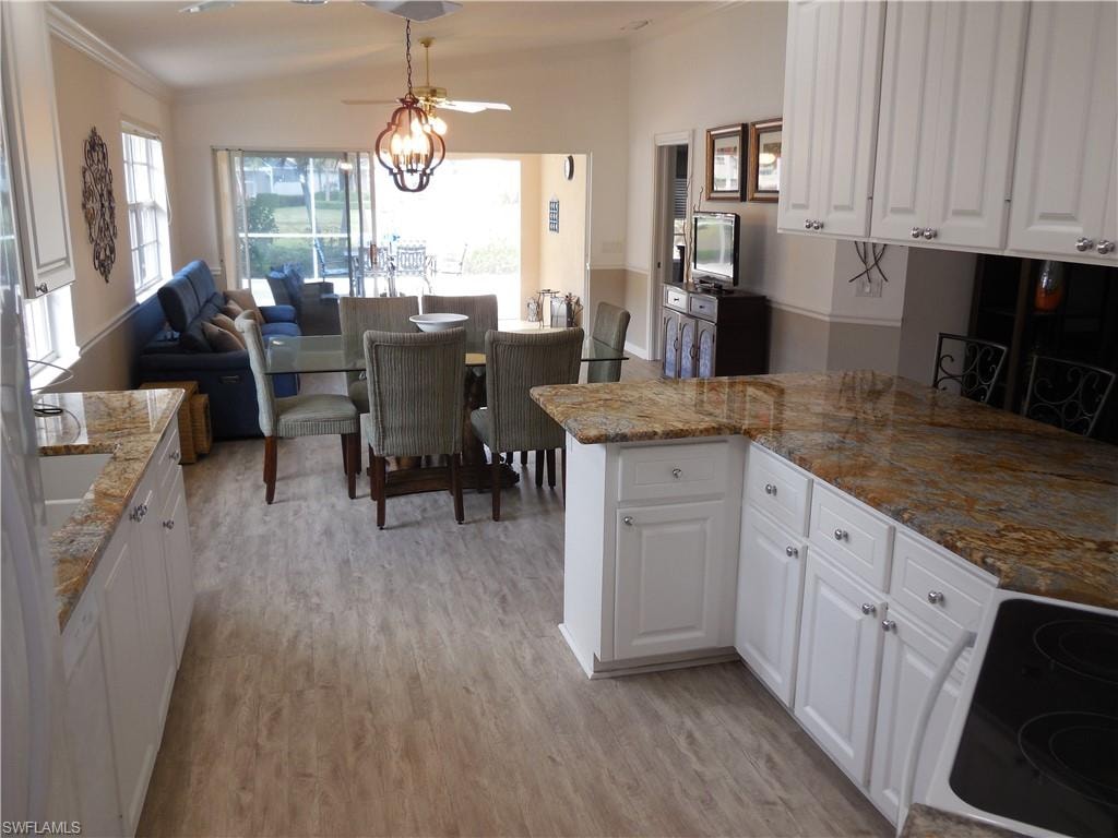 Kitchen featuring light wood-type flooring, electric stove, white cabinets, and light stone countertops