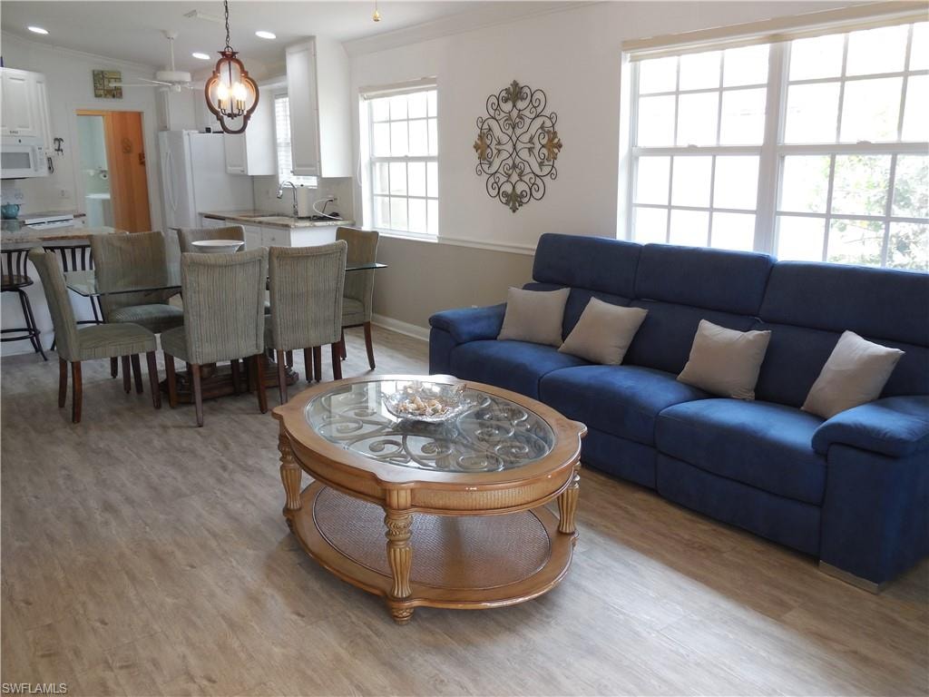 Living room with an inviting chandelier, baseboards, ornamental molding, and light wood finished floors
