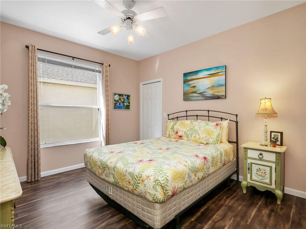 Wood-finish flooring, ceiling fan with integrated lighting, window with blinds, and a solid white door