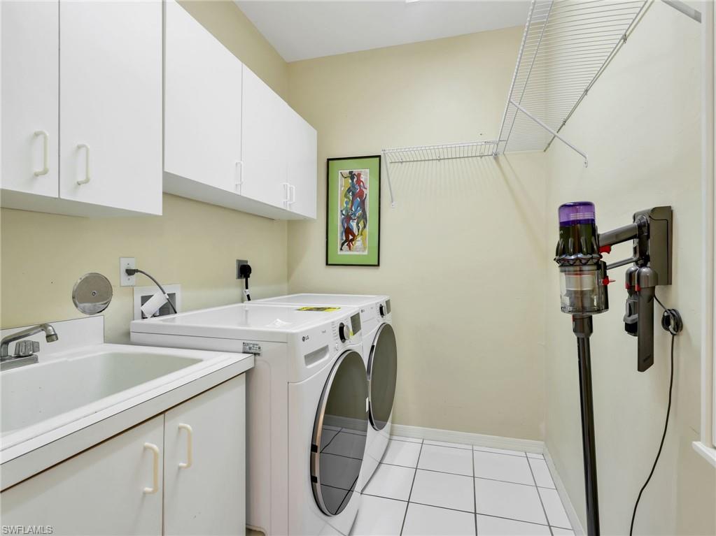 White cabinetry, utility sink, white front-load washer and dryer, white wire shelving, and square white floor tiles