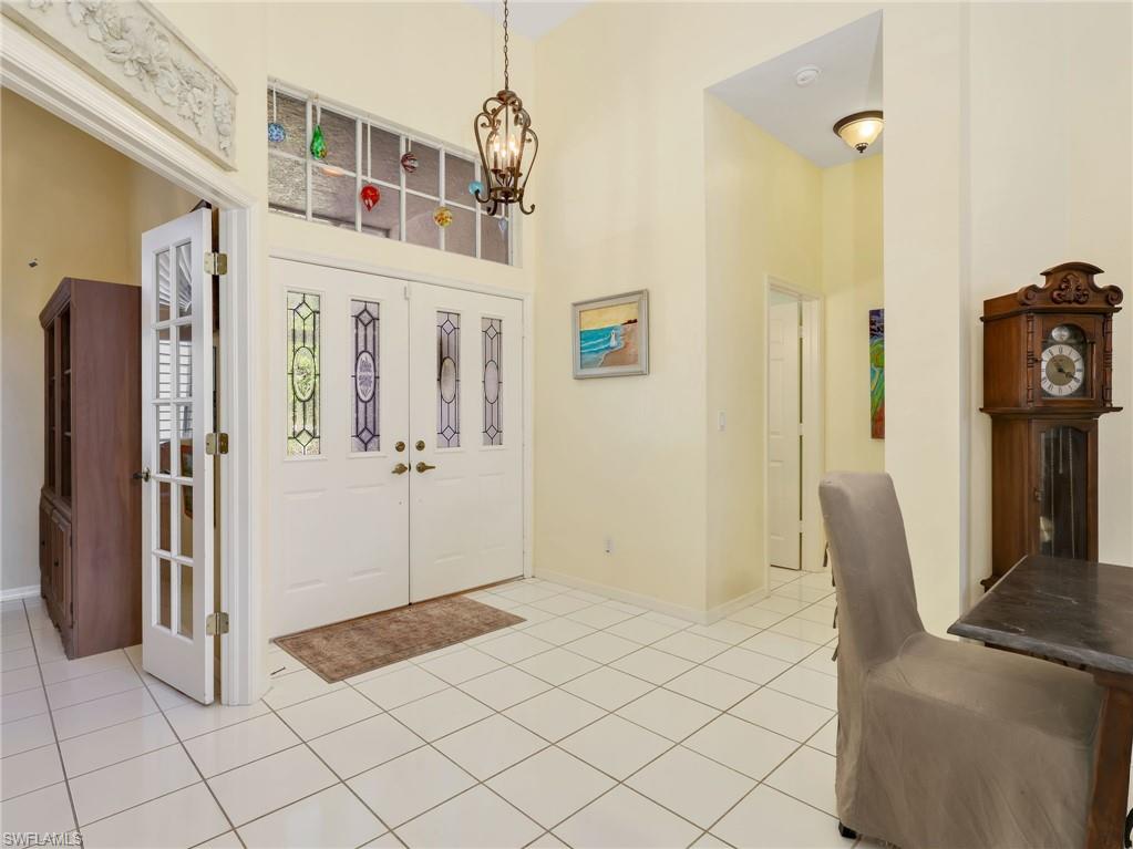 Double entry doors with decorative glass panels, transom window, and tiled flooring