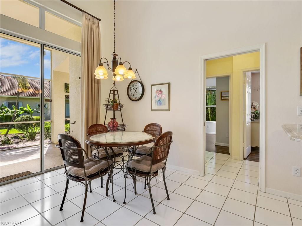 White square-tiled flooring, glass sliding door, transom windows, and a vaulted ceiling